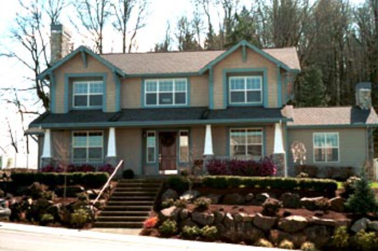 A two-story house with a blue upper level, beige lower level, white trim, a front porch, stone details, and landscaped garden with stairs.