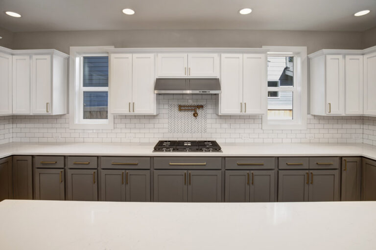 Modern kitchen with white countertops, gray cabinets, stainless steel appliances, a window, subway tile backsplash, and recessed ceiling lights.