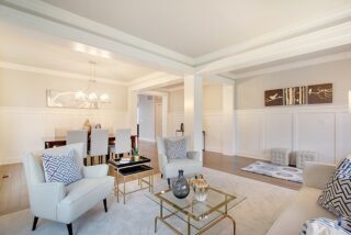 This image shows a bright, elegant living room with modern furniture, decorative pillows, a chandelier, and artwork on the walls, featuring a neutral color palette.