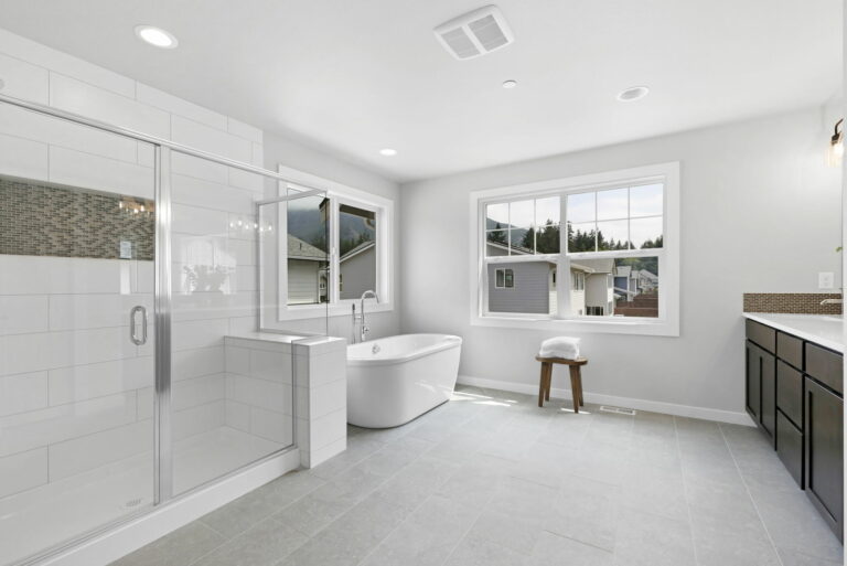 Modern bathroom with a walk-in shower, freestanding tub, double sink vanity, tiled floor, large windows, and neutral color palette. Bright and clean design.